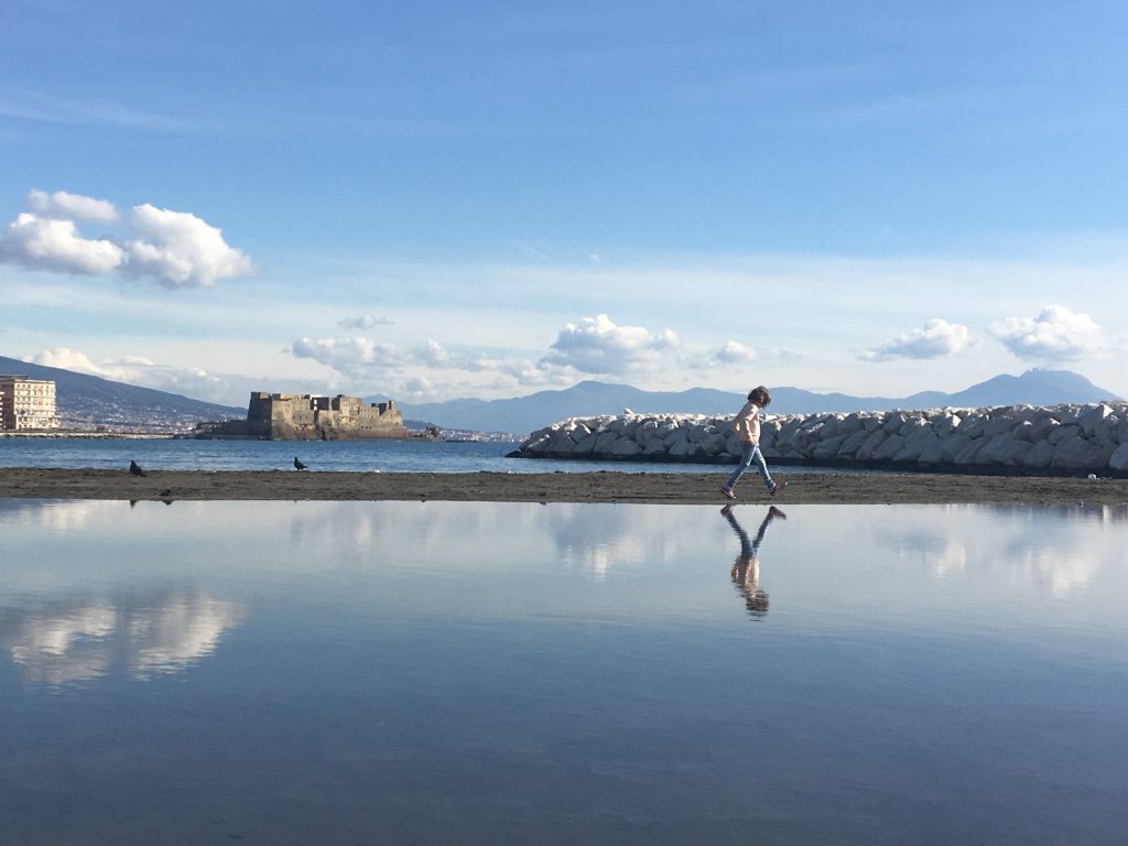 Riflesso nel mare di una bimba a mergellina con sfondo castel dell'ovo